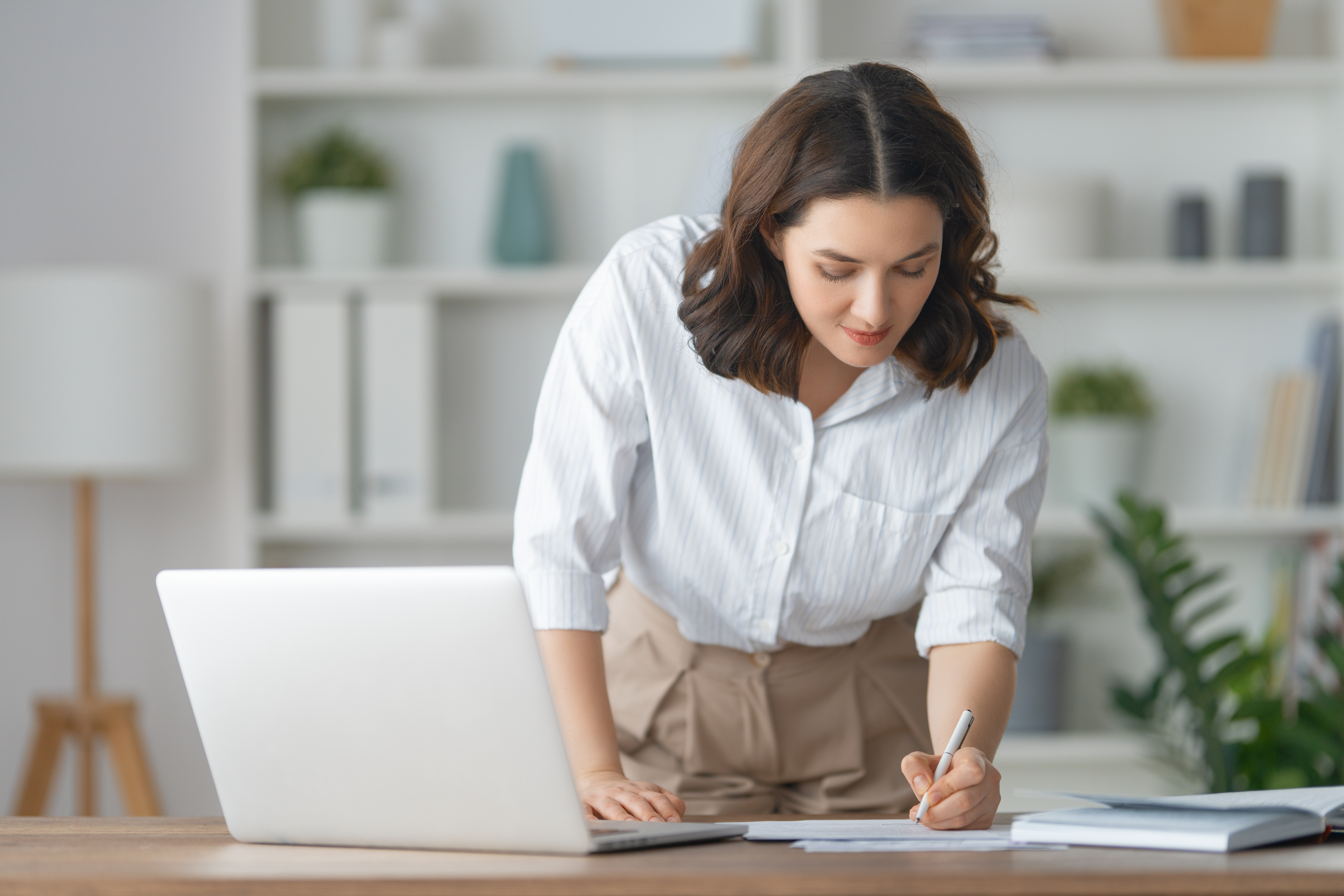 A woman balances her credit union checking account from her home office.