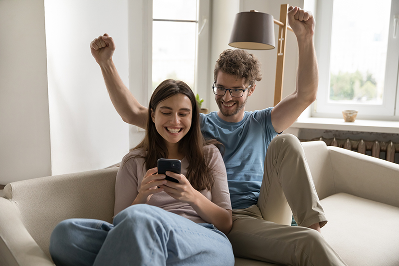 A young couple is celebrating the discovery of a basic checking account that offers a better banking experience.