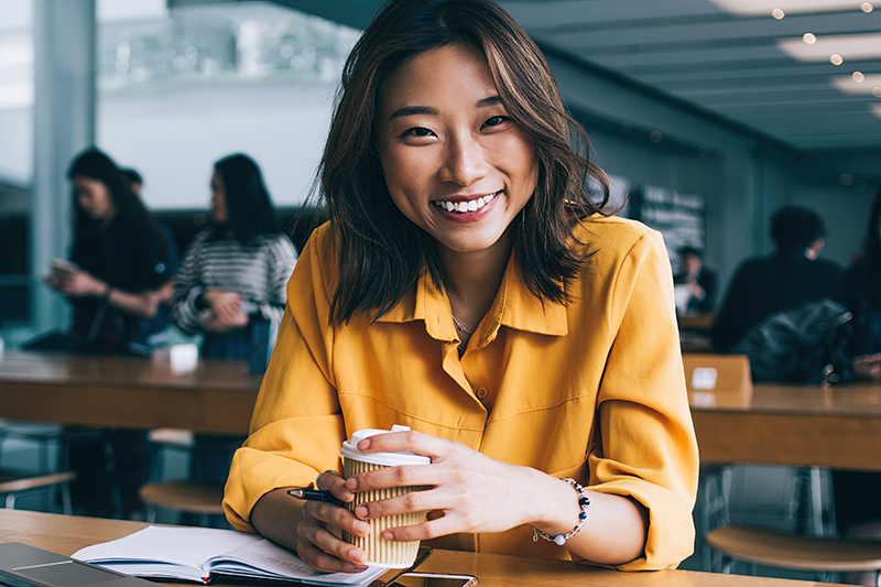 A young professional woman smiles after opening a free and unlimited checking account that will help her save money for her future.